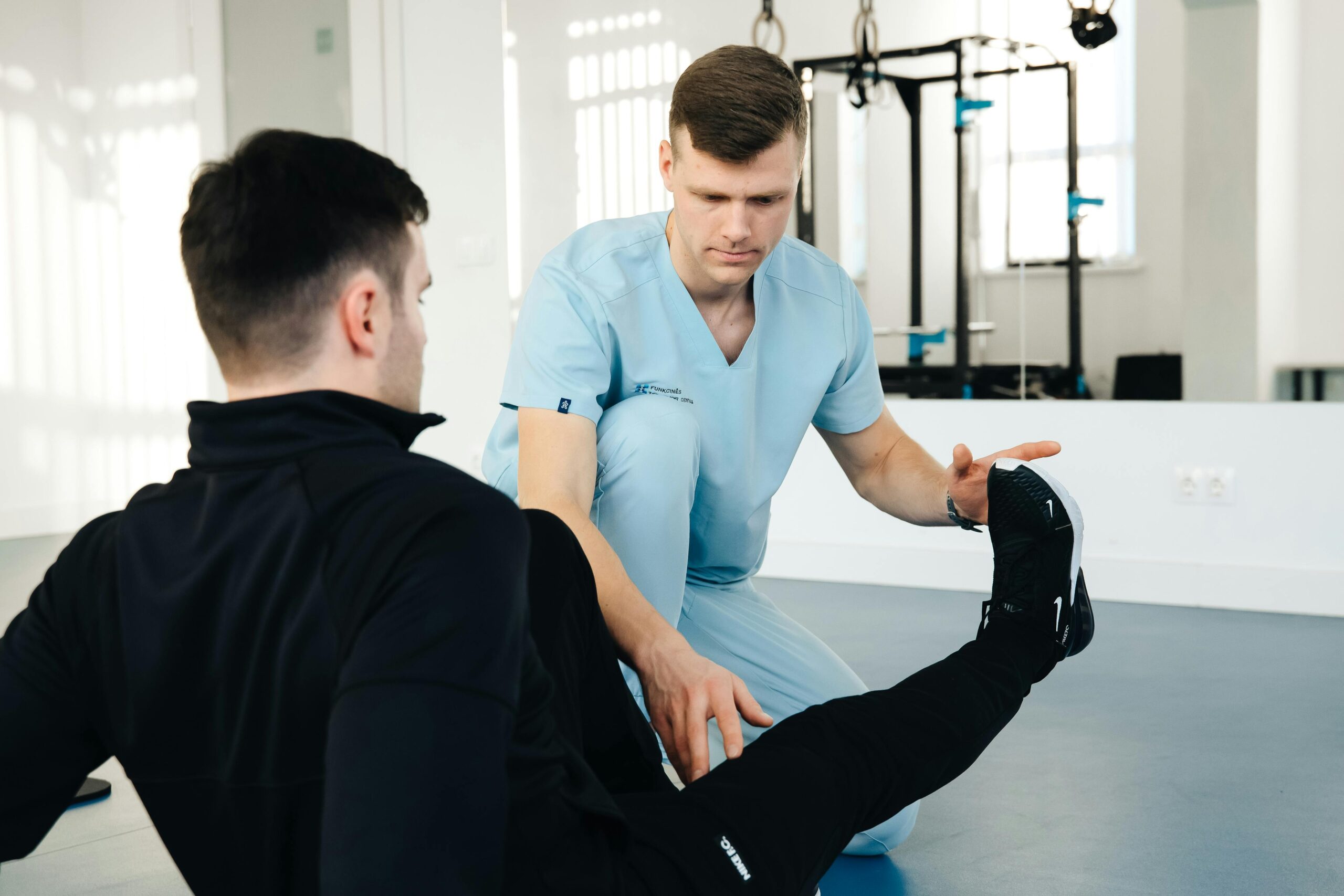 A physiotherapist assisting a patient in leg exercises during a rehabilitation session in a clinic setting.