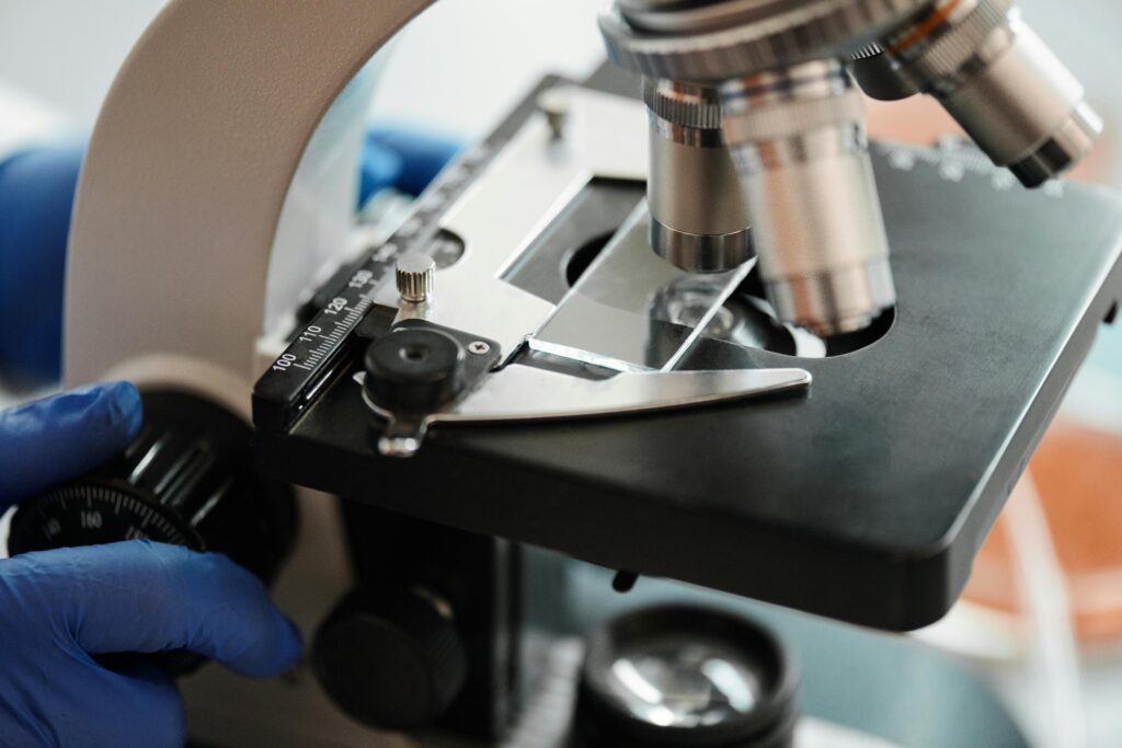 Detailed view of using a microscope with gloved hands in a lab setting.